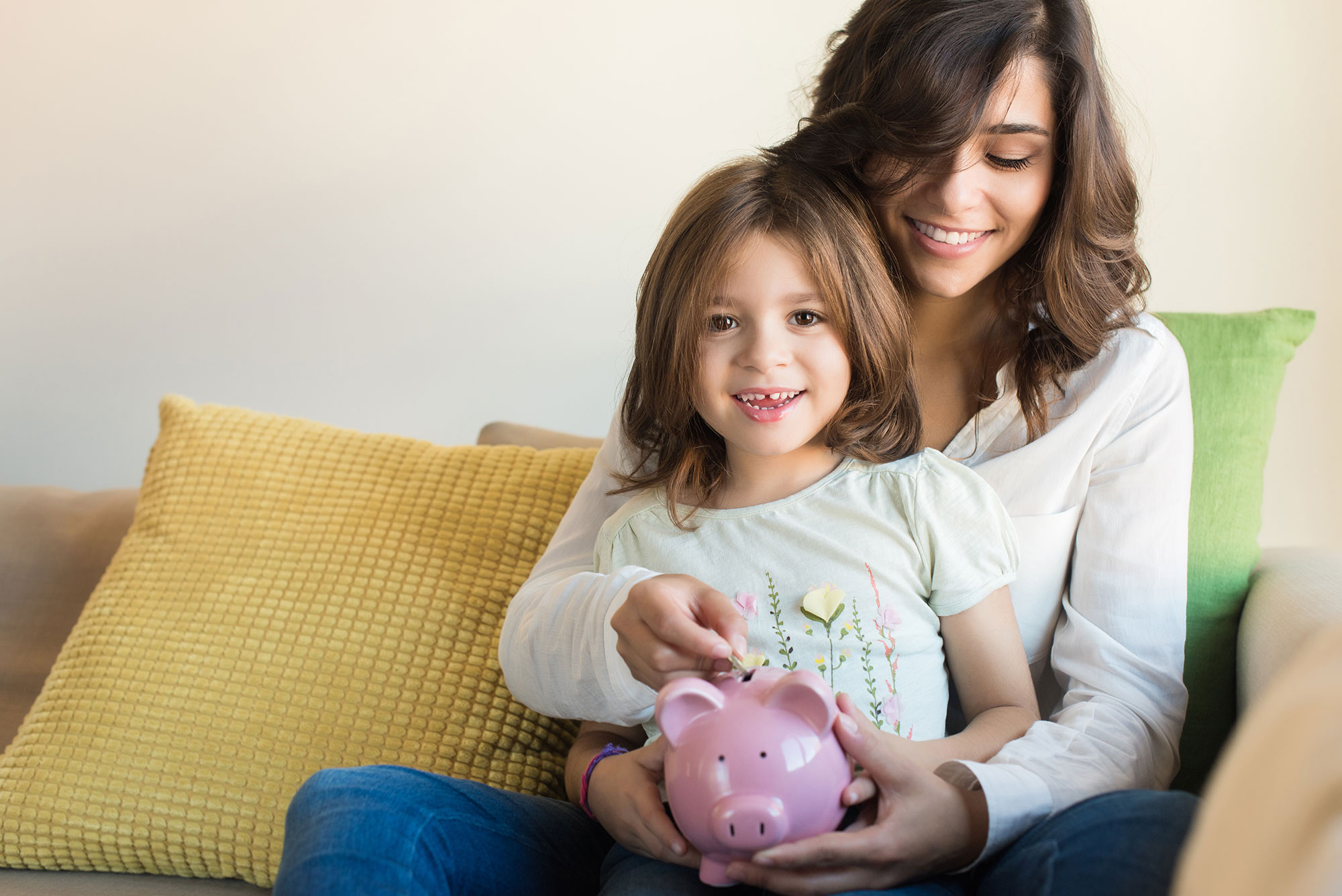A mother and daughter putting coins into a piggy bank
