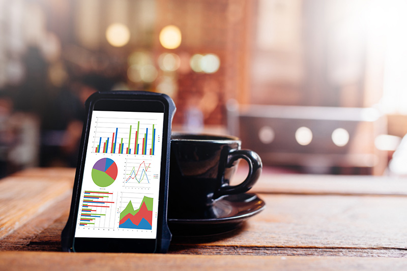 Financial charts on a smartphone beside a cup of coffee — the planning technology we use