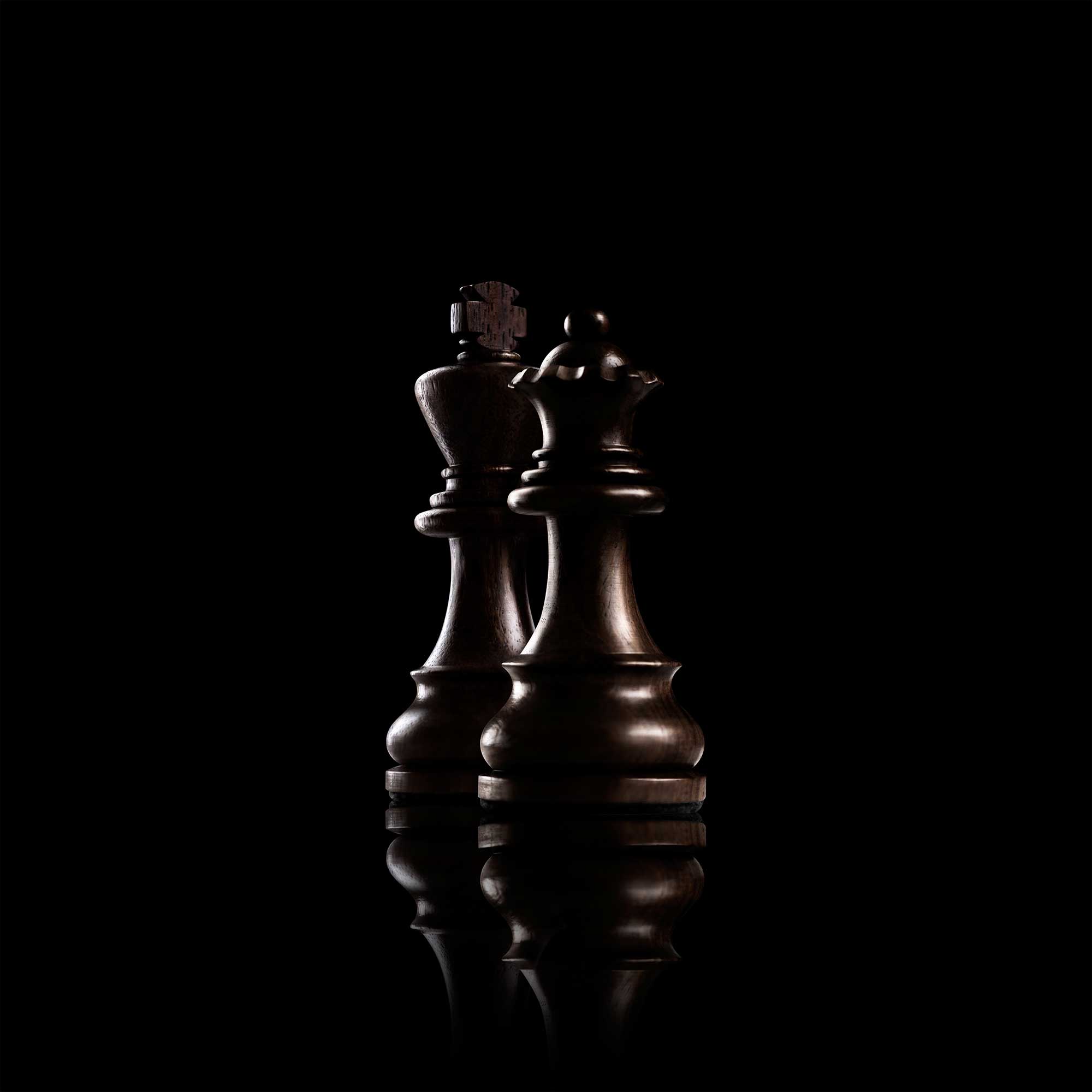 A chess king and queen, lit against a dark background — the long view we take of wealth management